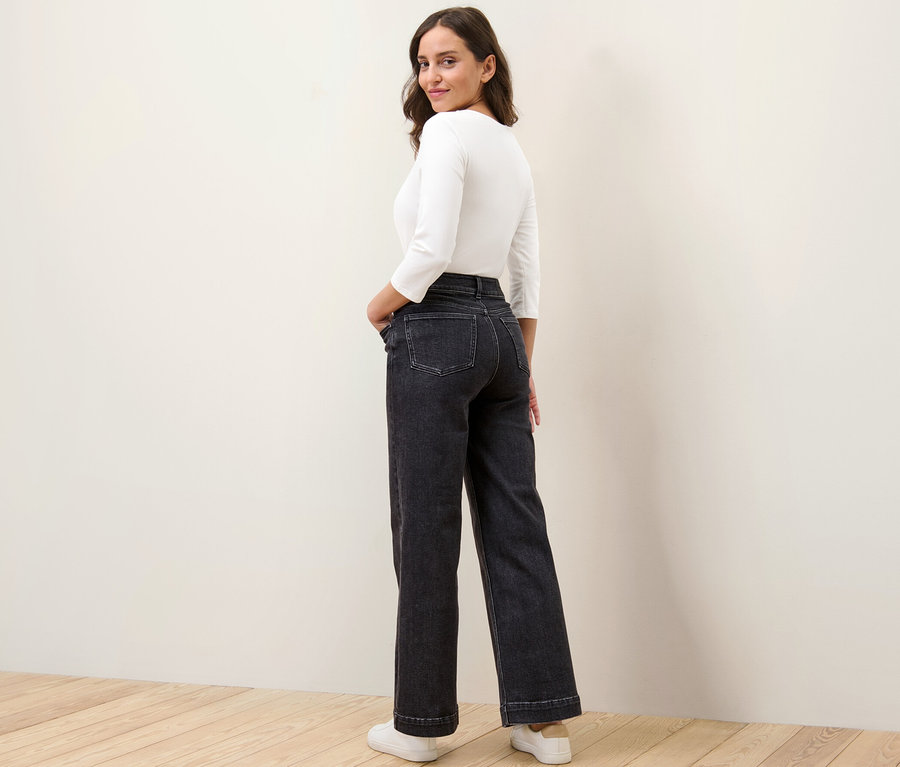 Eine Frau blickt über die Schulter und posiert in Wide Jeans – Fit »Viki«.