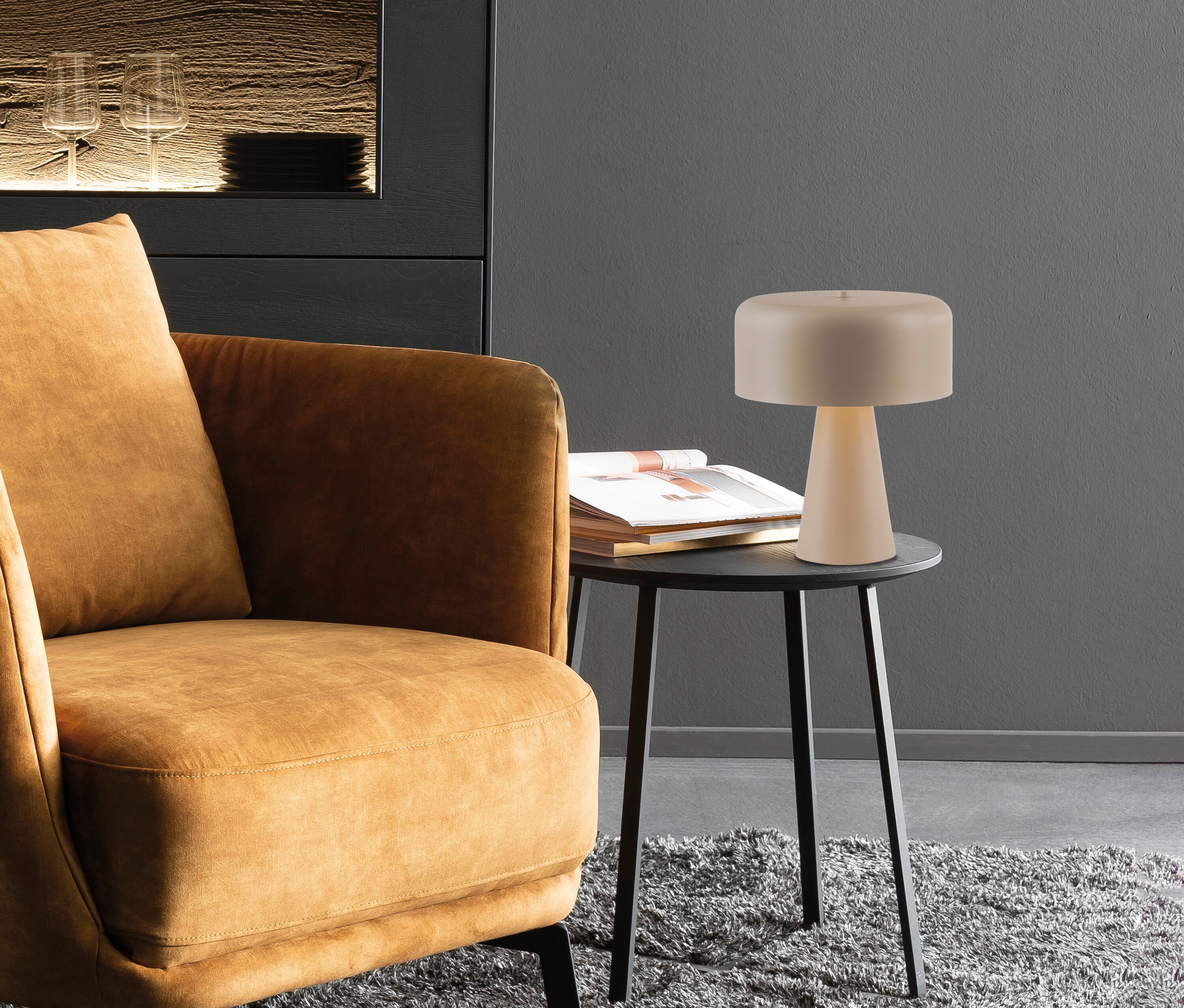 Detailaufnahme eines Wohnraums mit braunem Sessel, Lampe und Tisch mit Büchern.