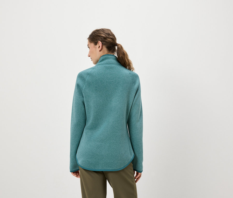 Frau von hinten trägt eine blaugrüne Fleecejacke und olivgrüne Hosen.