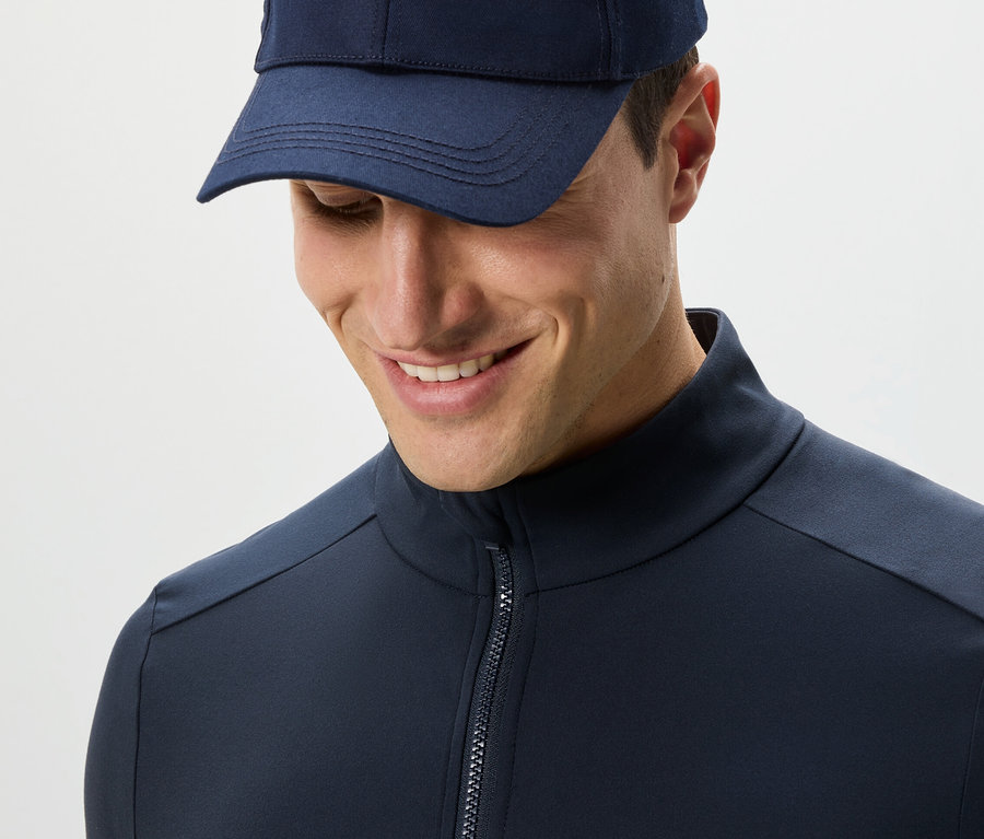 Mann in marineblauer Funktionsjacke und Kappe blickt nach unten.