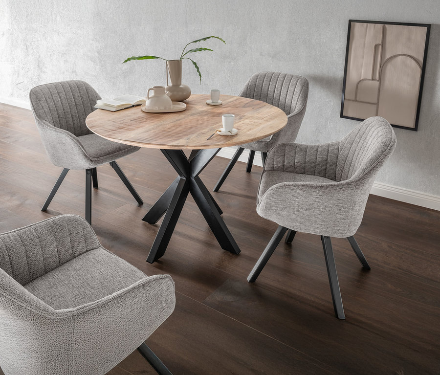 Ein runder Holztisch mit schwarzem Metallfuß steht in einem Raum mit vier grauen Stühlen, einer Vase und einem Bild an der Wand.