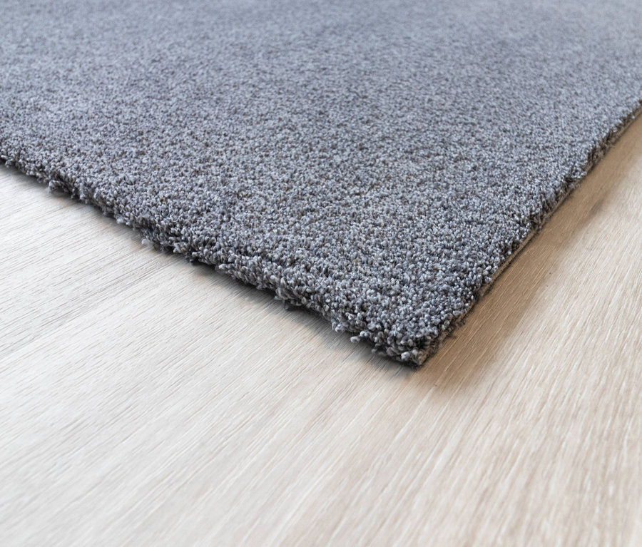 Nahaufnahme eines grauen Teppichs »Jane« auf einem Holzboden.
