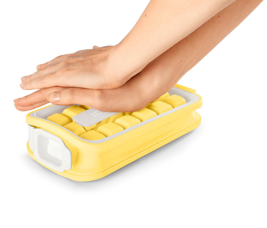 Hände drücken auf einen gelben Eiswürfelbereiter »ICEBREAKER® POP«, der mit gelben Eiswürfeln gefüllt ist.