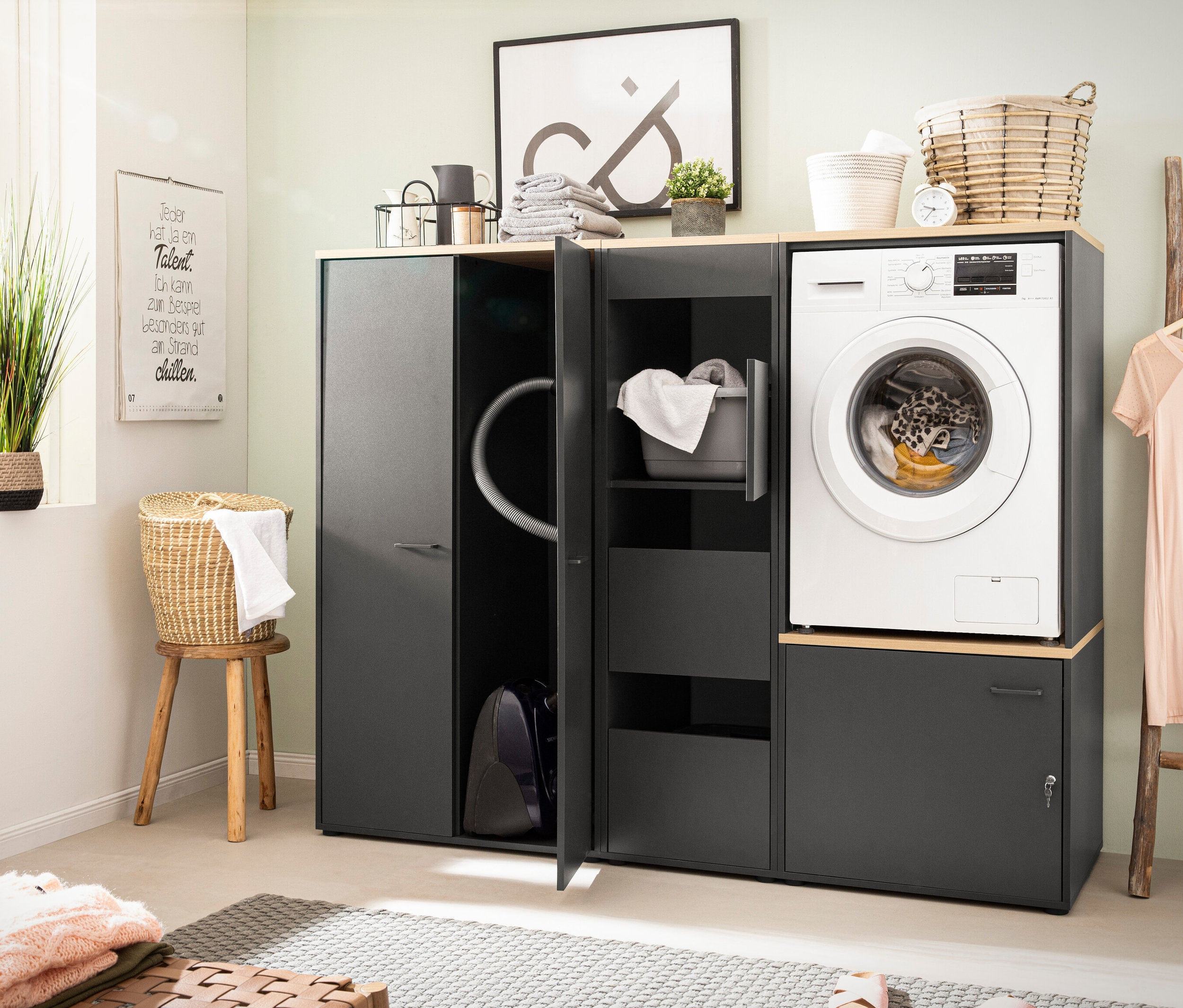 Waschmaschine auf Waschmaschinenumbau »Solea U670« in Anthrazit steht neben Hochschrank »Solea« in Anthrazit.