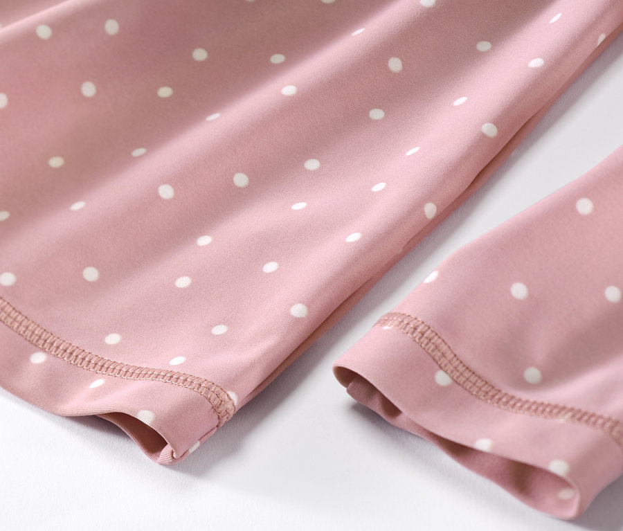 Detailaufnahme eines Kinder-Kombis mit UV-Schutzfaktor 80, mit Punkten auf rosa Stoff.