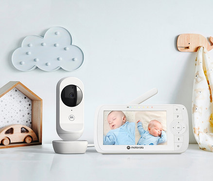 Auf einem weißen Tisch steht ein weißes Video-Twin-Babyphone »VM35-2« mit Kamera und Monitor, der zwei schlafende Babys zeigt.