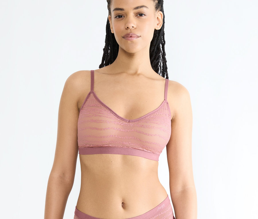 Frau mit dunklen Haaren und brauner Haut trägt einen spitzenbesetzten BH und Slips in Altrosa.