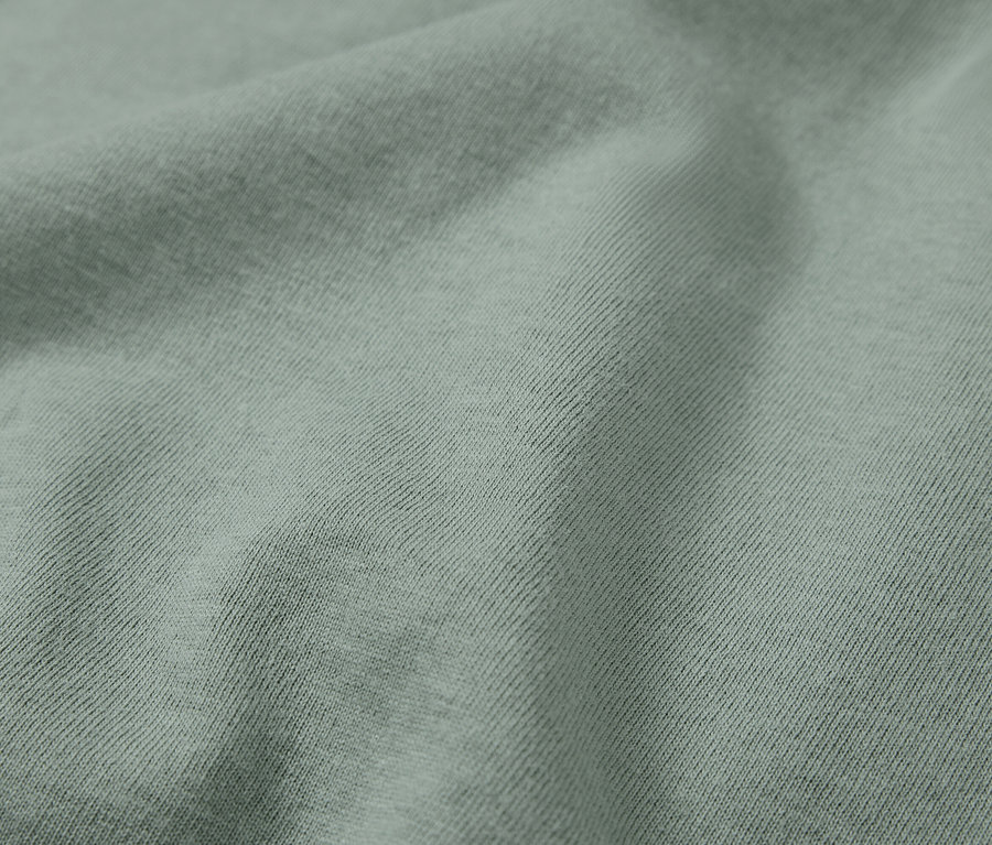 Detailaufnahme eines hellgrünen Stoffes mit diagonalem Rippenmuster.