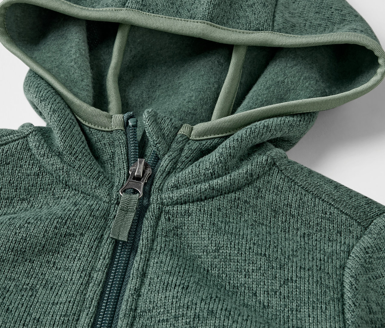 Detailaufnahme einer Kinder-Strickfleecejacke mit Reissverschluss und Kapuze.