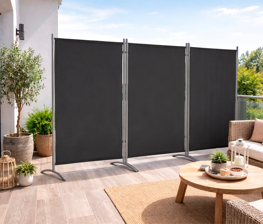 Auf einer Terrasse steht eine anthrazitfarbene, dreiteilige Leco Stellwand.