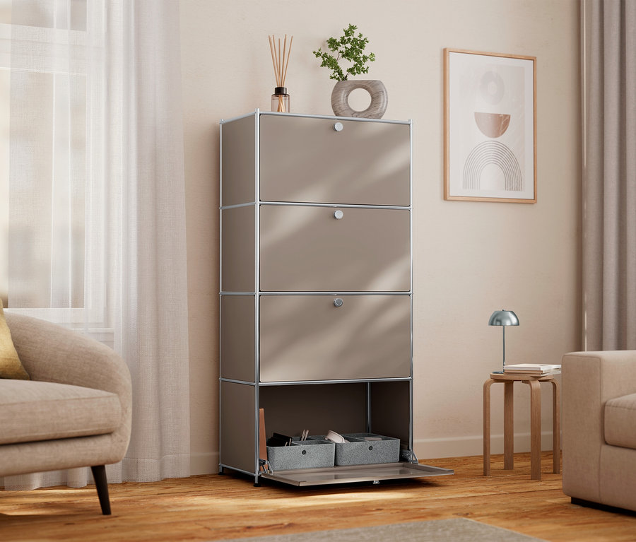 Einrichtungsszene mit einem hohen, beige Schrank mit vier Fächern, von denen eines offen ist und graue Aufbewahrungsboxen zeigt. Auf dem Schrank stehen eine Zimmerpflanze und Duftstäbchen.