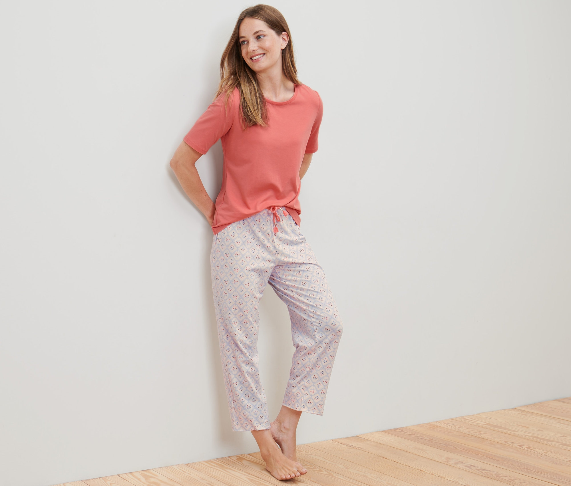 Frau lehnt an der Wand und trägt einen 7/8-Pyjama.