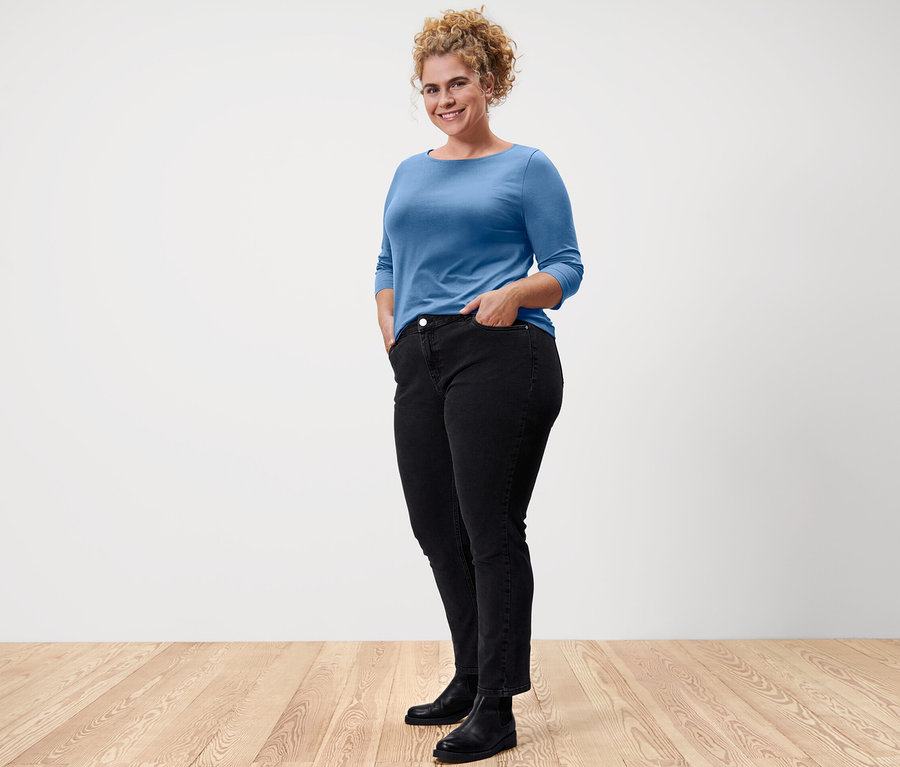 Frau posiert in einem hellblauen Shirt mit 3/4-Arm.