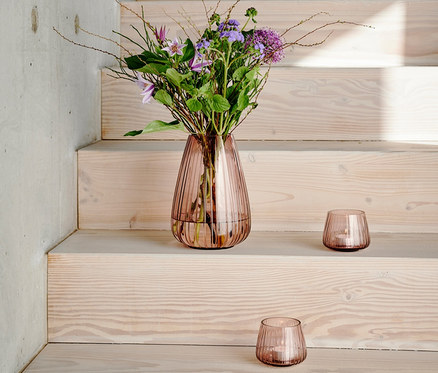 Blumen in Vase und zwei rosafarbene Bitz Kusintha Teelichthalter auf Treppe.