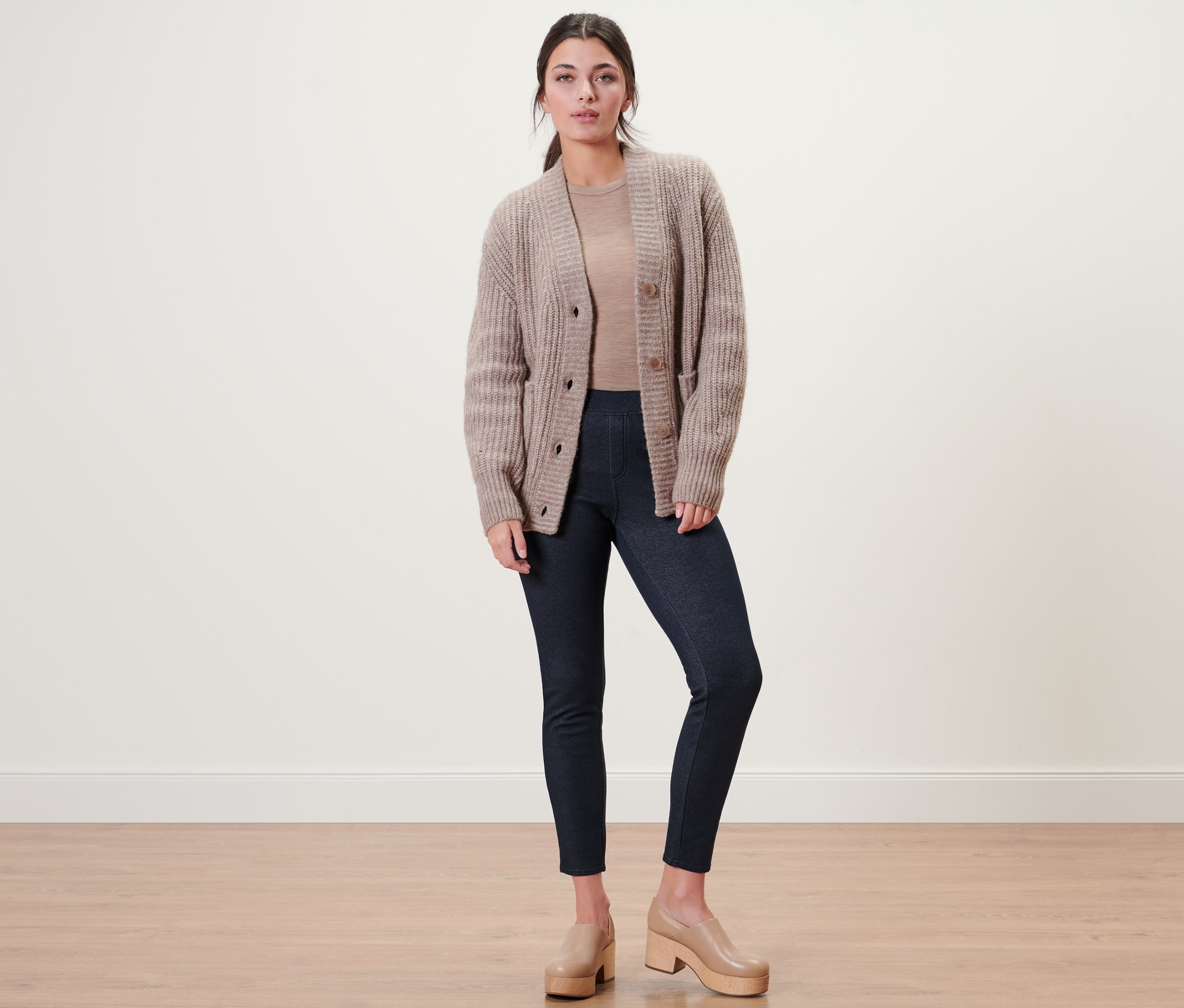 Frau posiert in gefütterten Leggings in Jeansoptik, Strickjacke und hellbraunen Plateauschuhen.