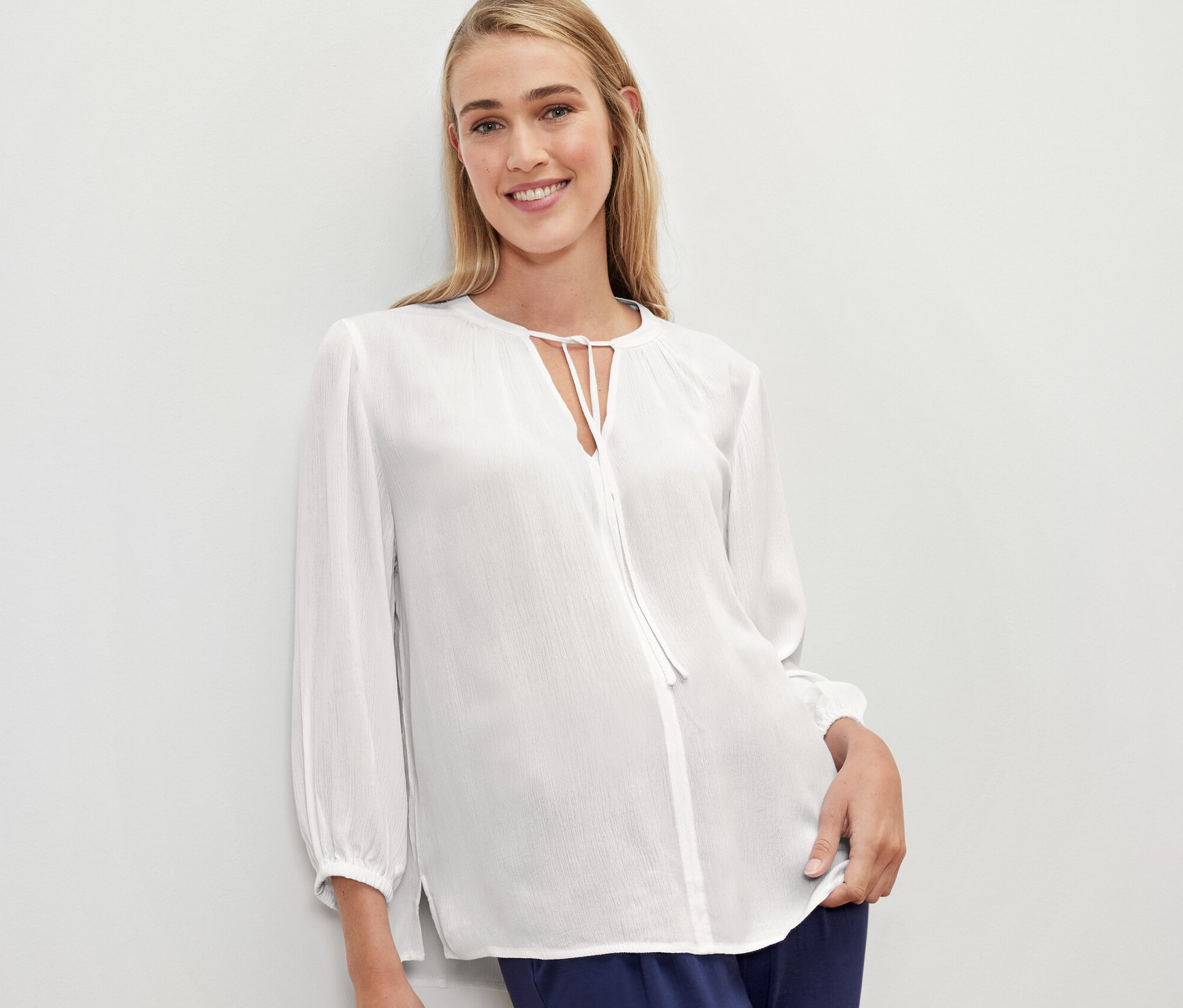 Eine Frau trägt eine weiße Tunika-Bluse.