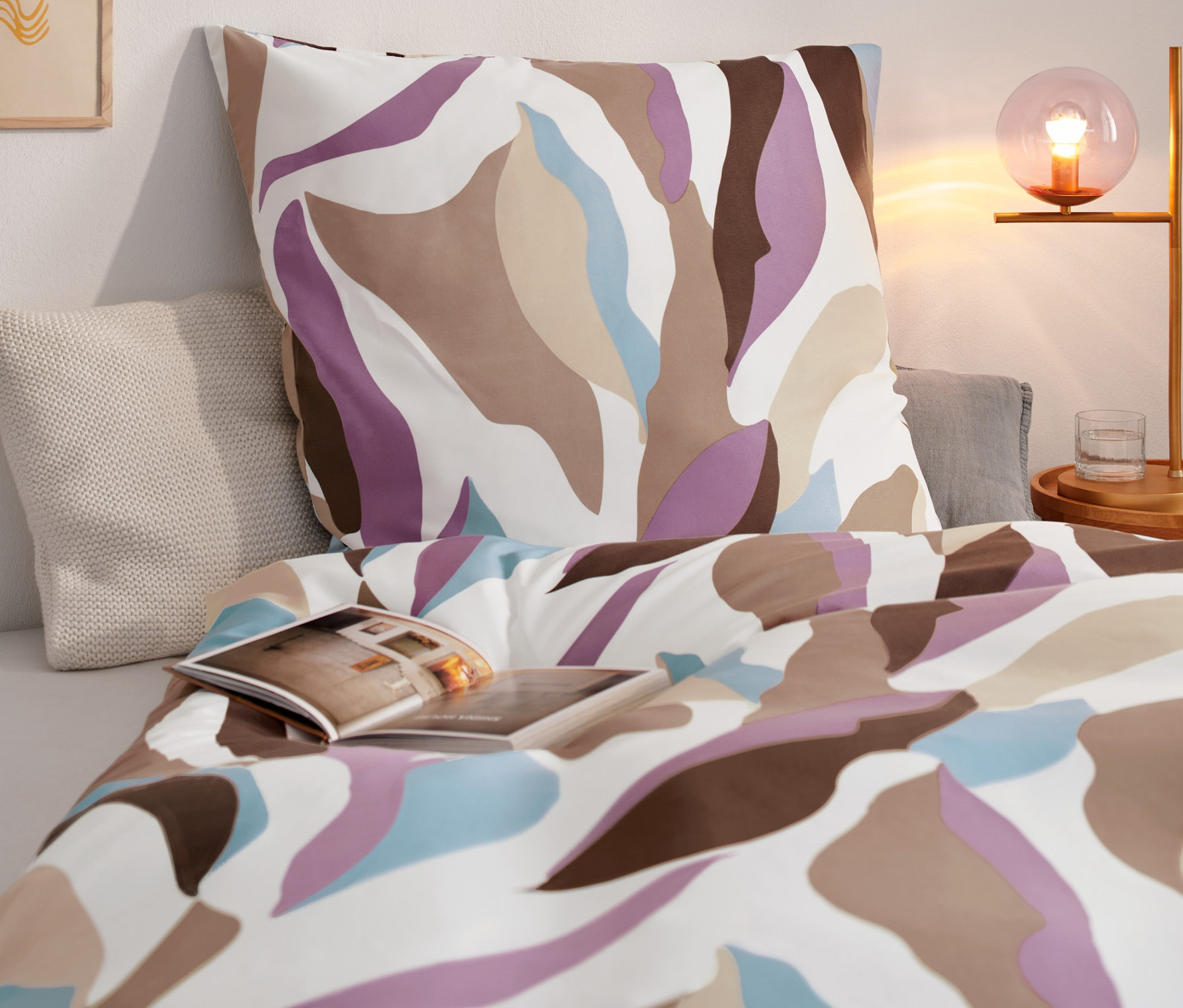 Gemusterte Microfaser-Bettwäsche auf einem Bett mit einem Buch.