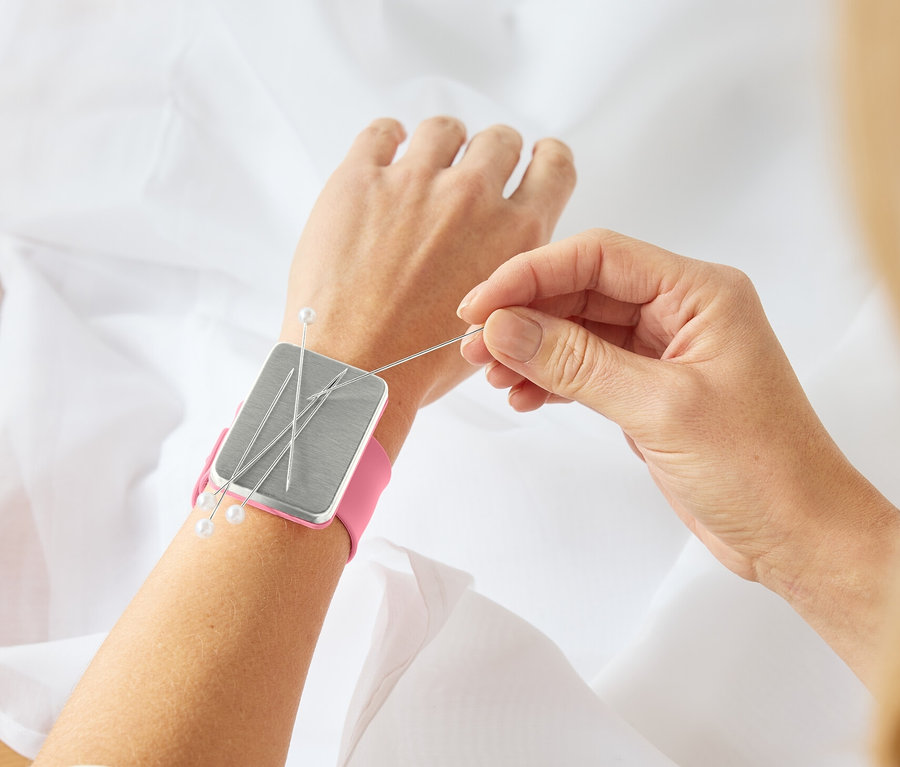 Frau näht Stoff mit Armnadelkissen, magnetisch, am Handgelenk.