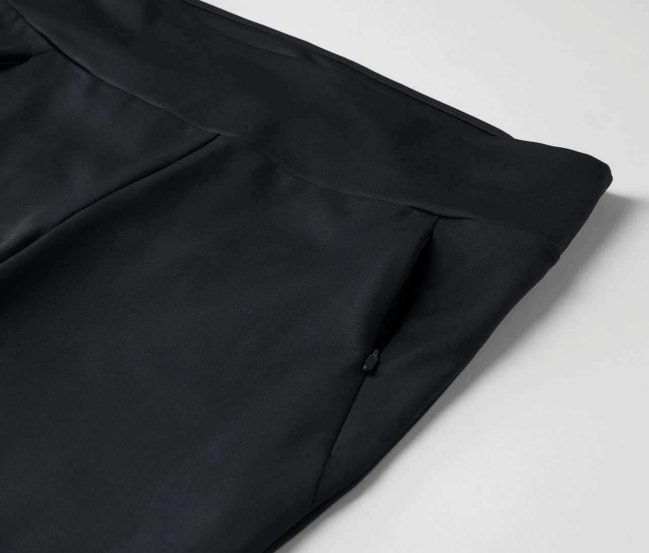 Detail einer schwarzen Hose mit Reißverschlusstasche.