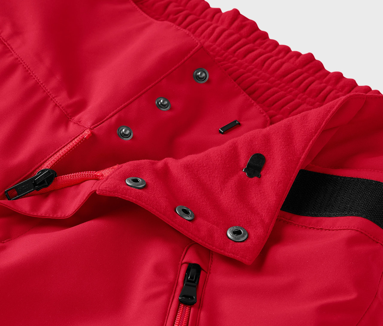 Detail einer roten Hose mit Reißverschluss und Druckknöpfen.