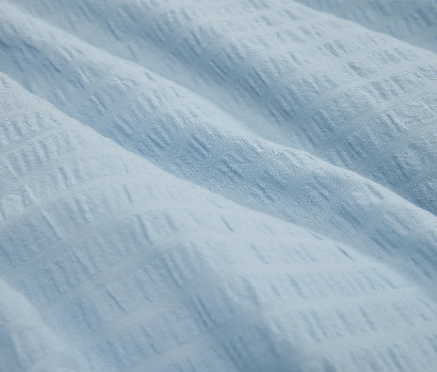 Detailaufnahme eines hellblauen Stoffes mit Textur.