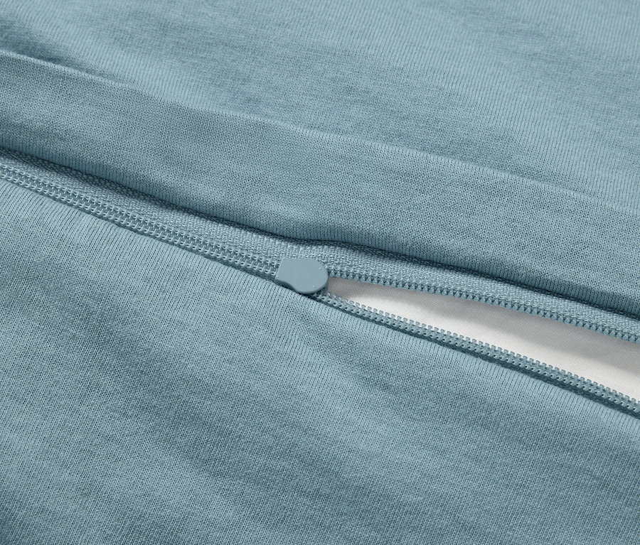 Nahaufnahme eines hellblauen Bettbezugs mit Reißverschluss und einem Stück weißem Stoff.