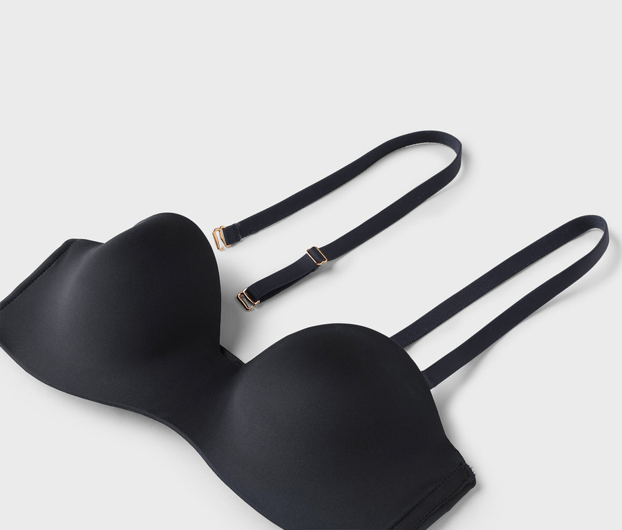Nahaufnahme eines schwarzen trägerlosen BHs mit abnehmbaren Trägern auf weißem Hintergrund.