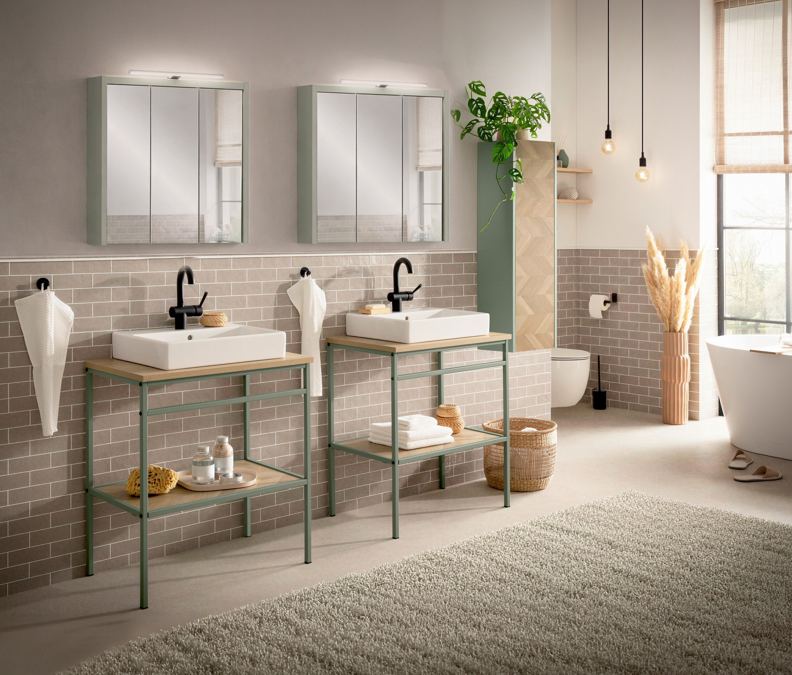 Badezimmer mit zwei Waschtischen »Lorna« in Fischgräte Pistazie, weißen Aufsatzbecken und schwarzen Armaturen vor grauer Ziegelwand.