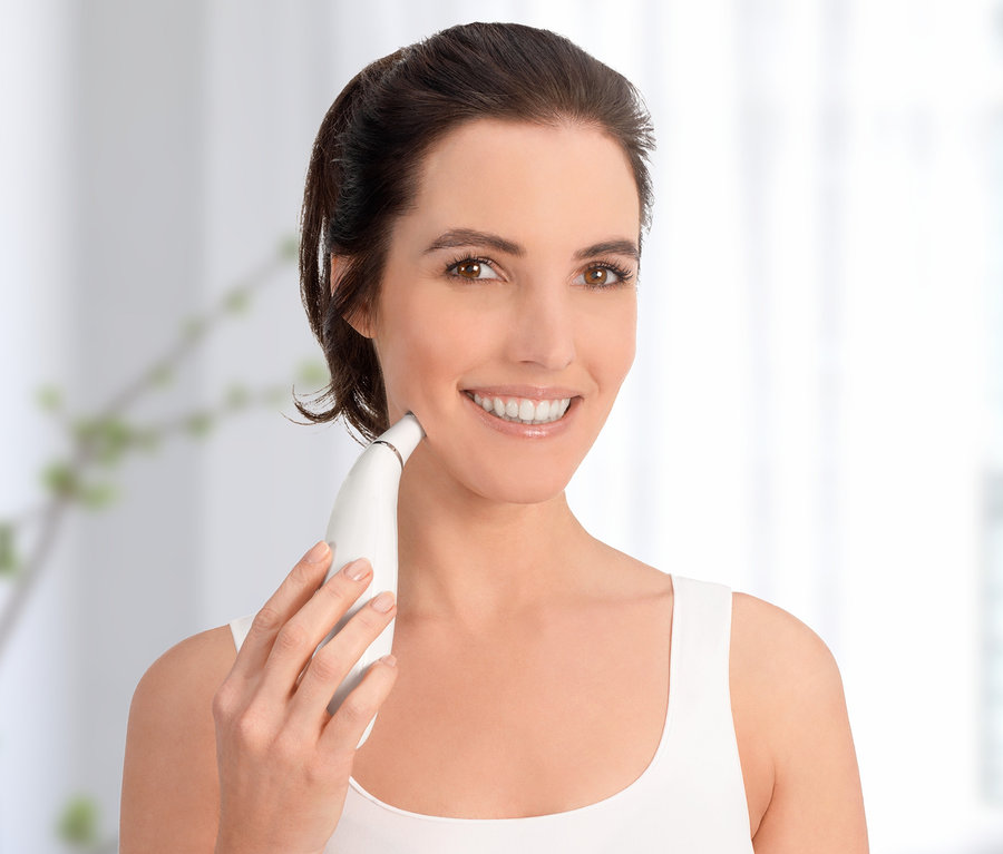 Frau verwendet weißes Silk’n-Mikrodermabrasionsgerät »ReVit Prestige« im Gesicht.
