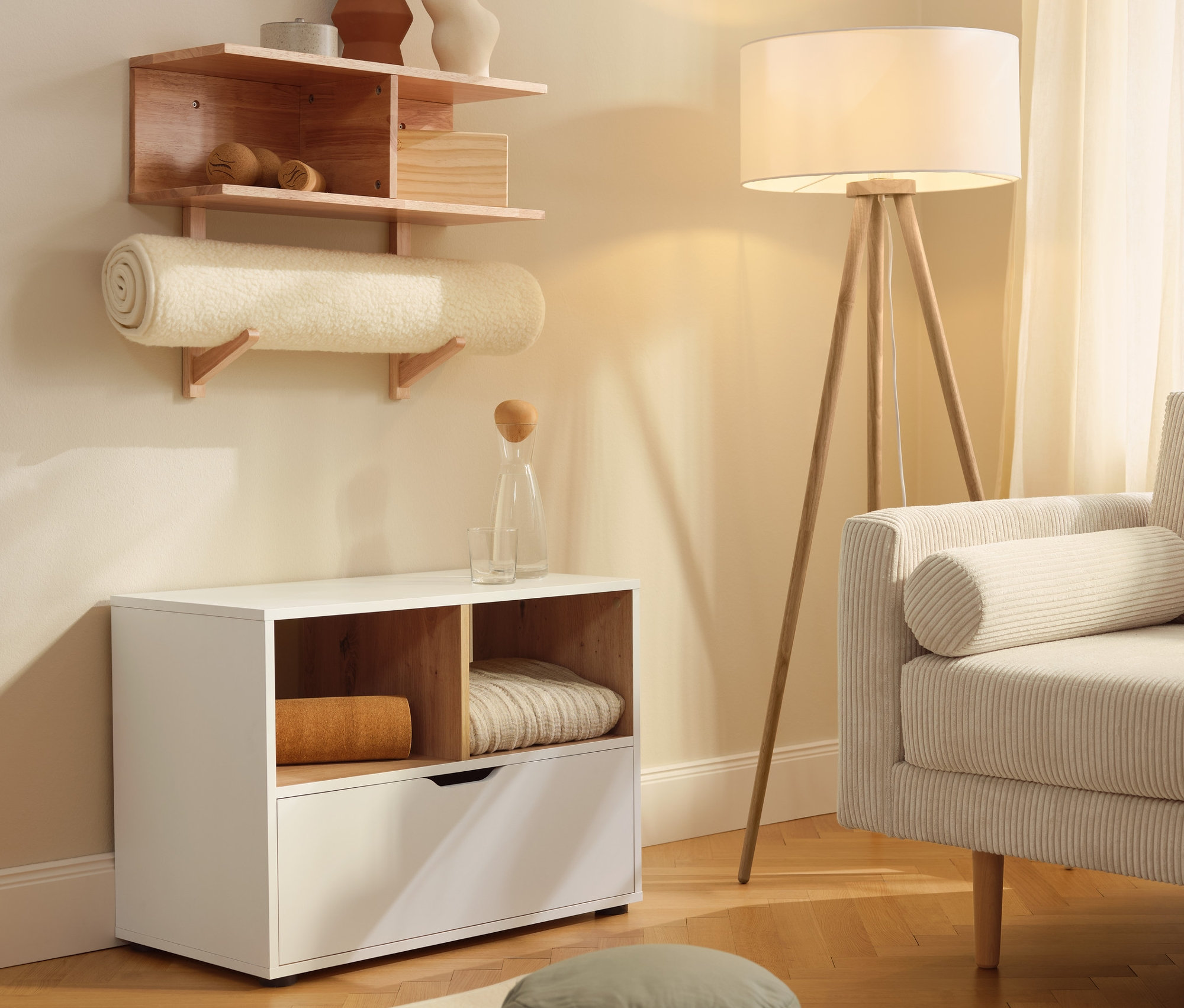 Ein Sideboard mit Schublade steht neben einer Schurwoll-Yogamatte. An der Wand hängt ein Wandregal.