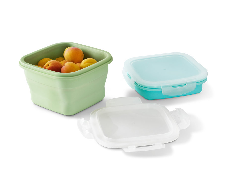 Eine grüne Frischhaltedose gefüllt mit Aprikosen und zwei leere Frischhaltedosen.