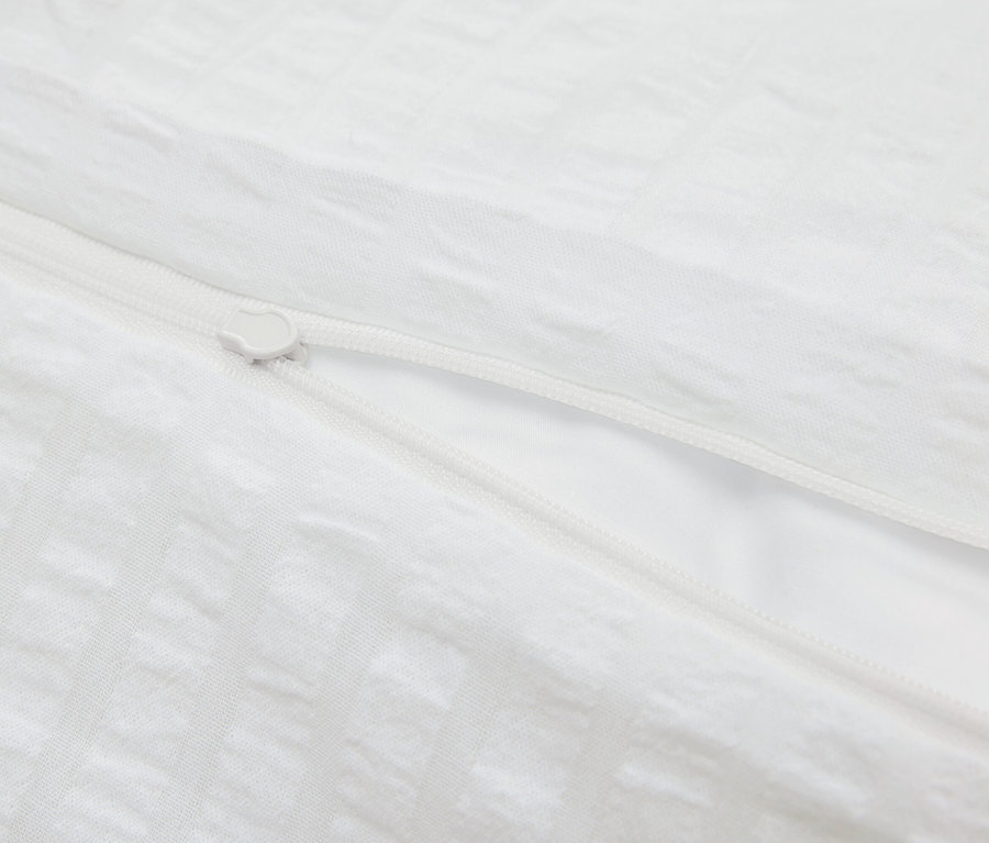 Detailaufnahme eines weißen Bettbezugs mit Reißverschluss.