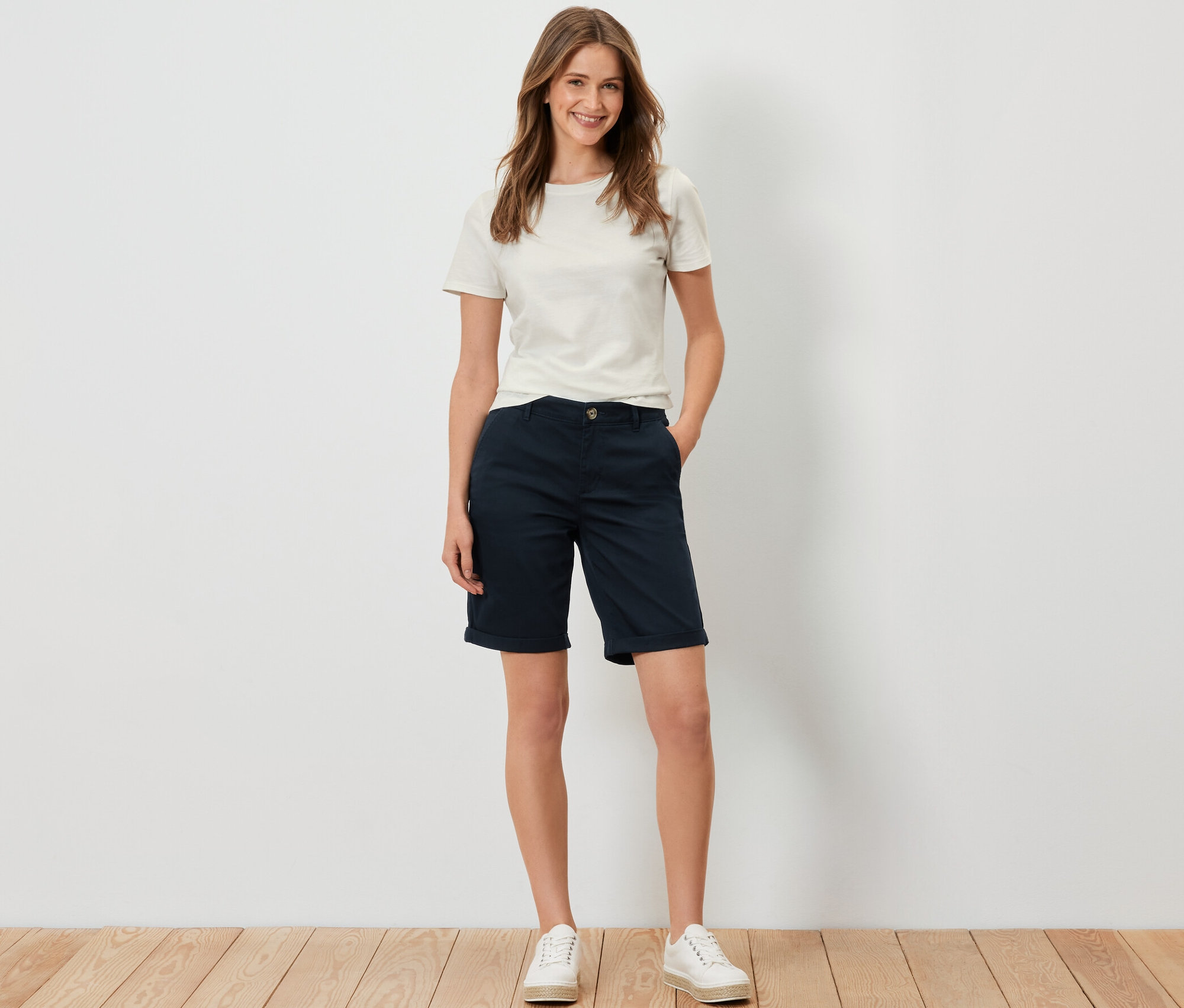 Frau steht und trägt Chino-Shorts, navy.