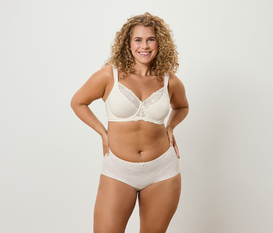 Frau mit lockigem Haar posiert in Unterwäsche.