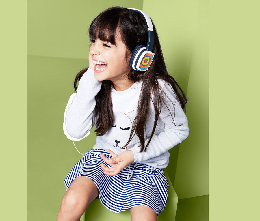 Lächelndes Mädchen sitzt und trägt Kinder-Kopfhörer mit austauschbaren Malkarten.