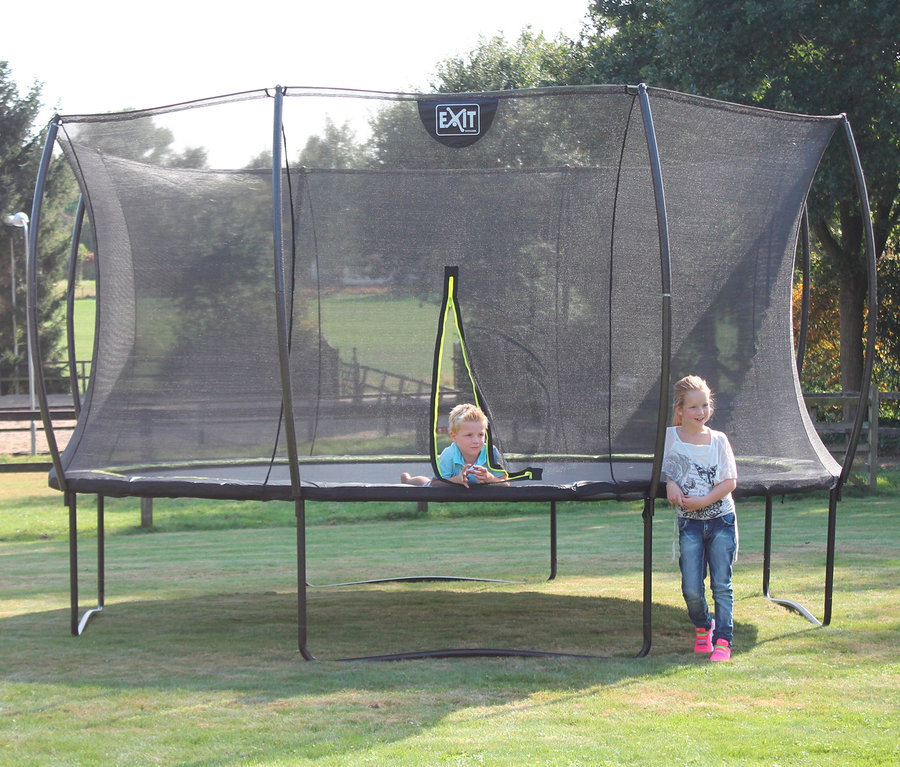 Kinder spielen auf einem EXIT Trampolin »Silhouette 305« auf einer Wiese.