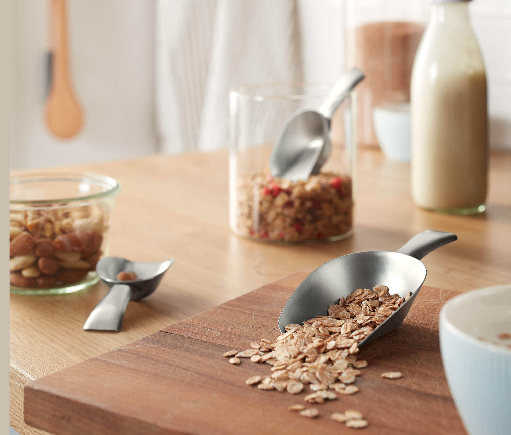 Haferflocken werden von einer der 3 Dosierschaufeln auf ein Holzbrett geschüttet.