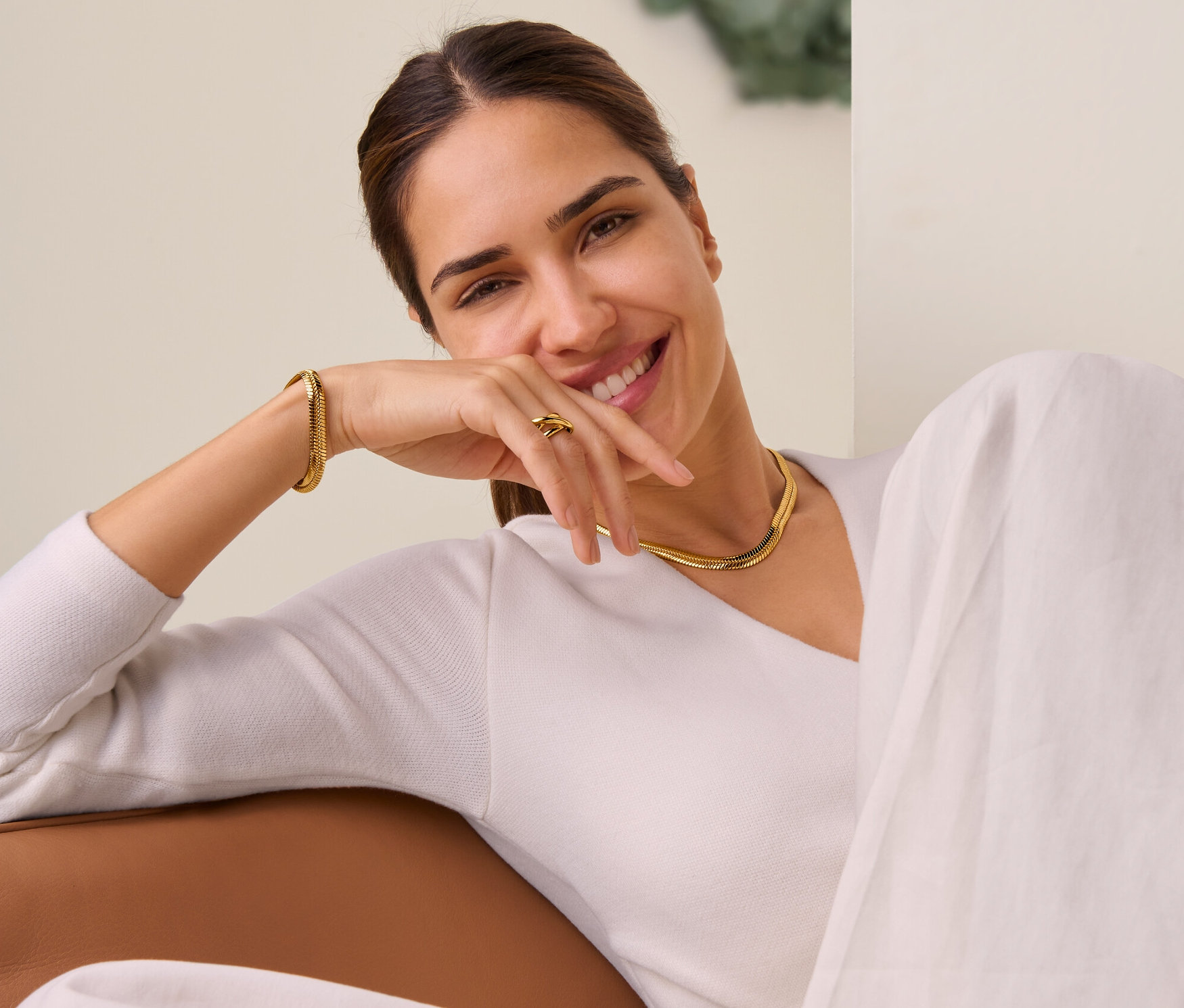 Lächelnde Frau liegt und trägt Kette flache Schlange, Armband flache Schlange und Ring Loops.