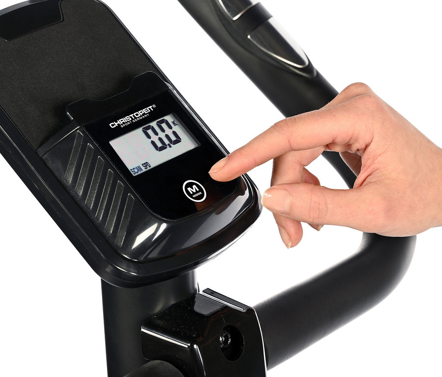 Finger drückt Knopf auf dem schwarzen Display eines Heimtrainer 2.2 in Holzoptik.