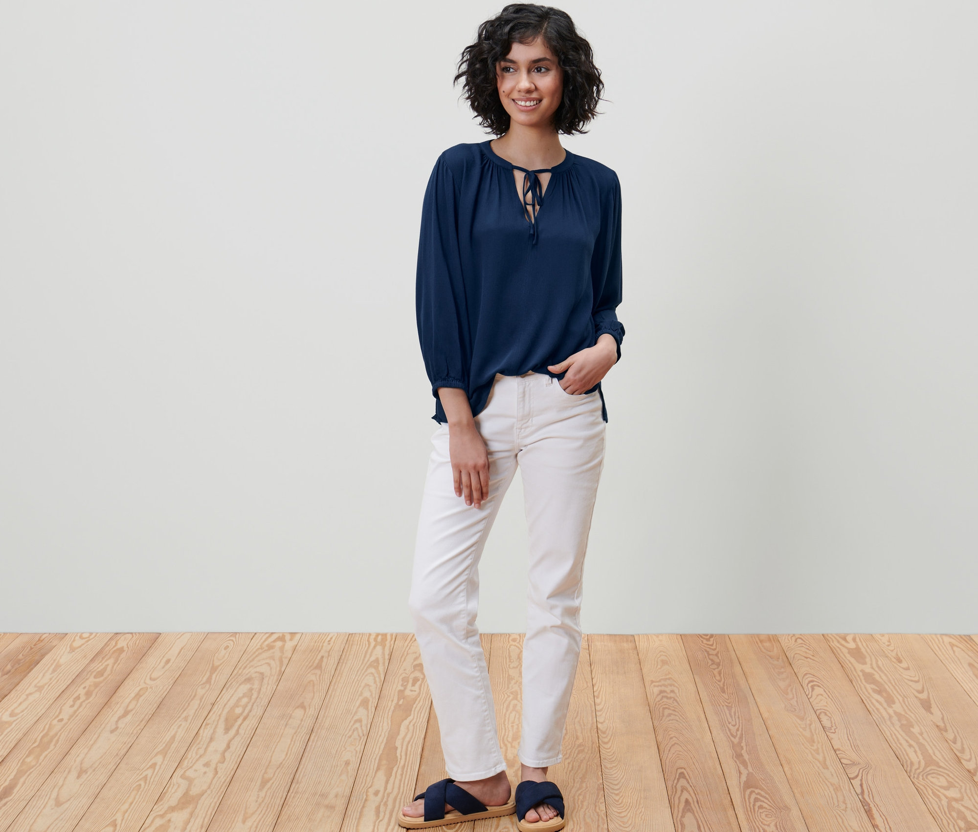 Frau steht und trägt eine blaue Tunika-Bluse.