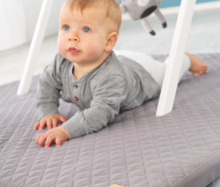 Baby liegt auf dem Bauch auf roba Spiel- und Krabbelmatratze.