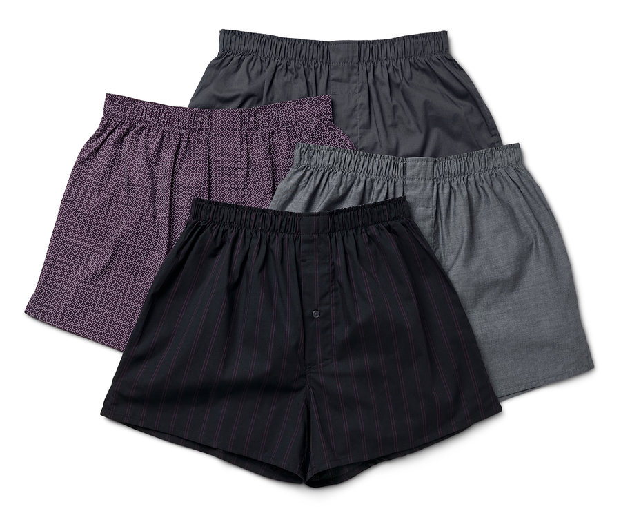 Vier Herren Boxershorts in verschiedenen Farben und Mustern liegen übereinander.