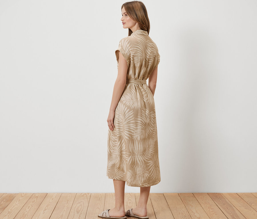 Frau steht seitlich und trägt ein bedrucktes Leinenkleid.