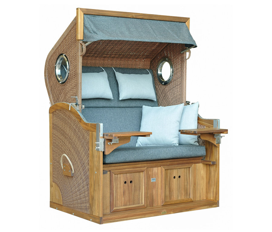 Nahaufnahme eines DeVries Strandkorbs, Akazie, XL mit blau-grauen Polstern und ausklappbaren Tischen.