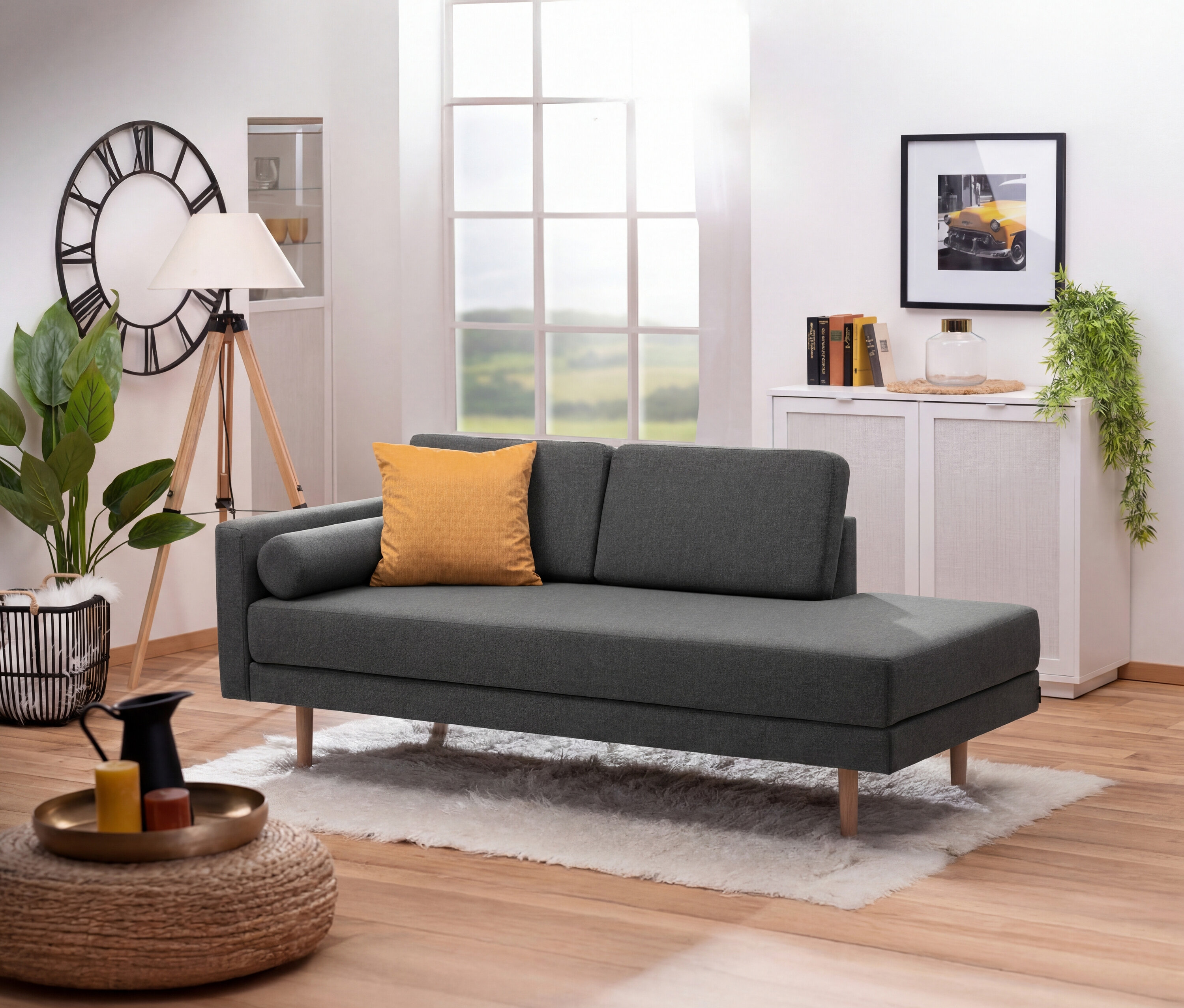 Anthrazitfarbene Récamiere »Ivo« mit verstellbarer Armlehne links mit gelbem Kissen auf Teppich vor Fenster.