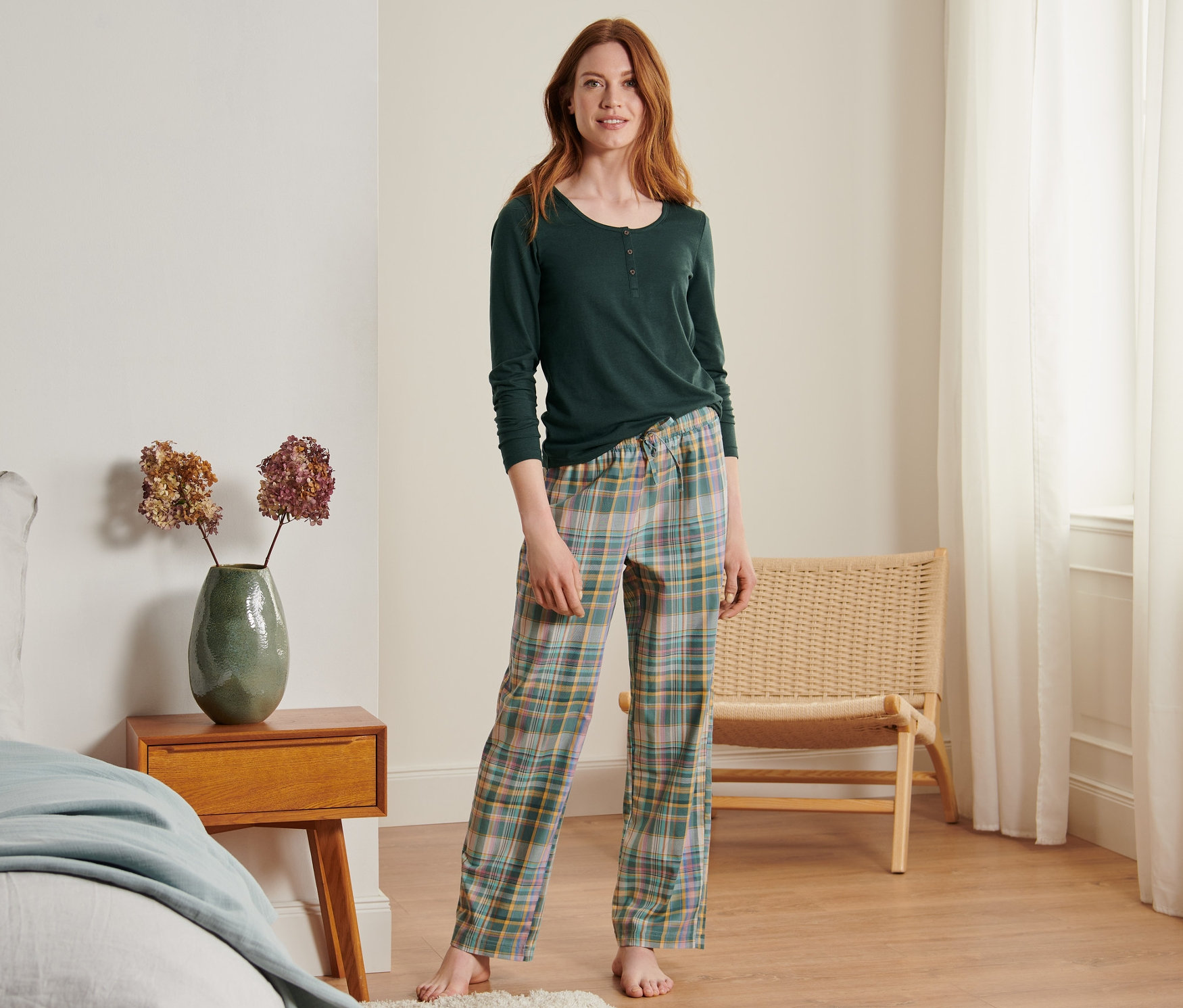 Eine Frau steht in einem Schlafzimmer und trägt einen Pyjama.