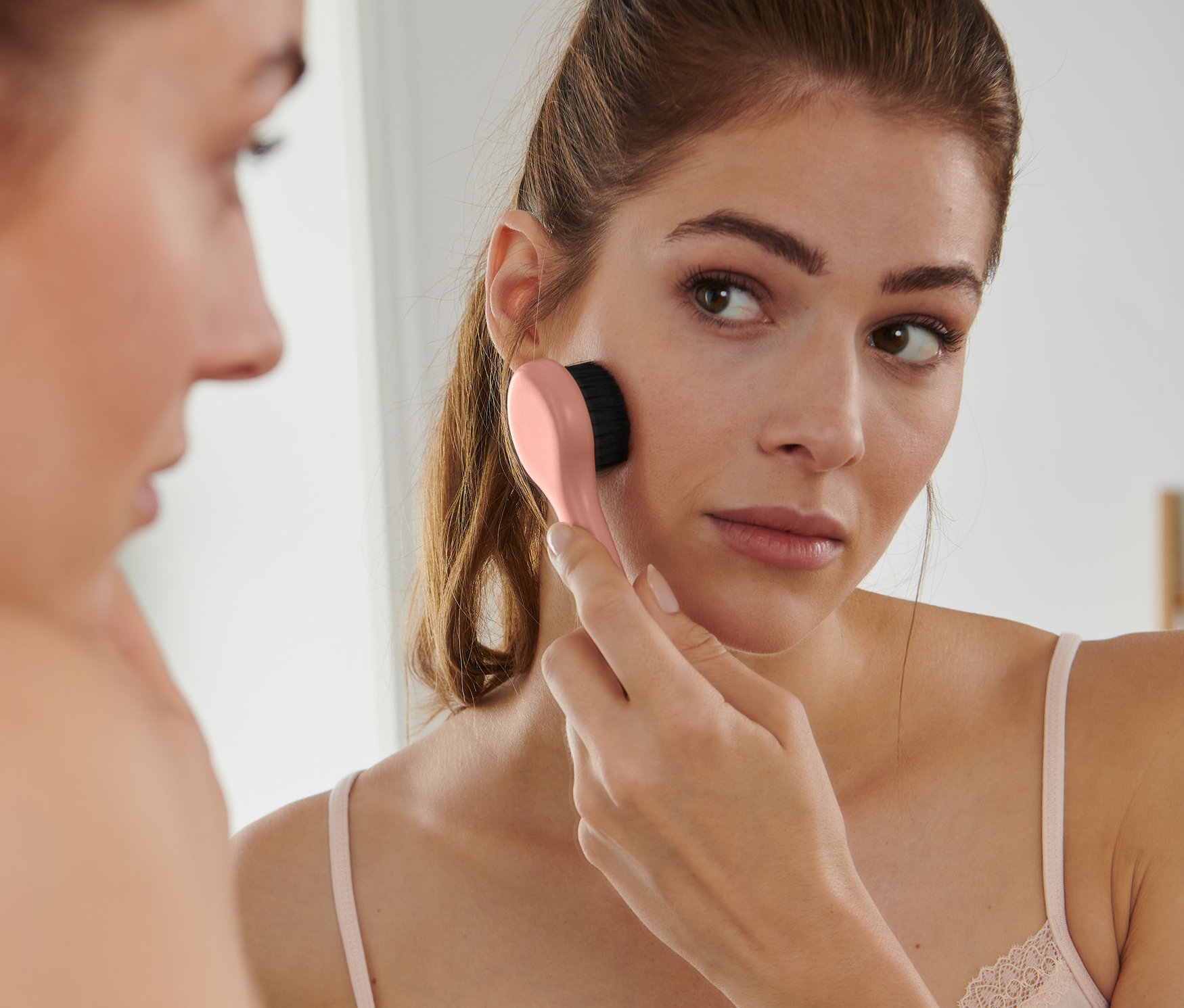 Frau massiert ihr Gesicht mit einer Kupfer-Gesichtsmassagebürste.