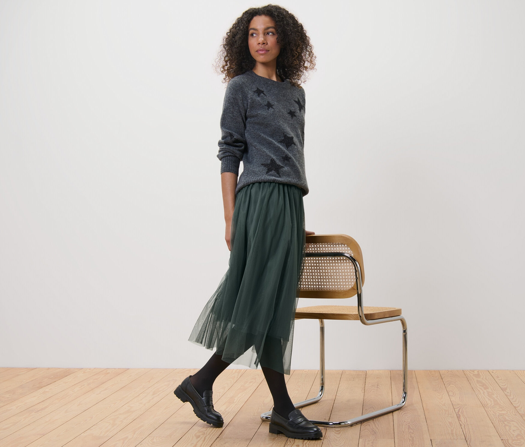 Frau trägt grauen Sternpullover und Tüllrock.