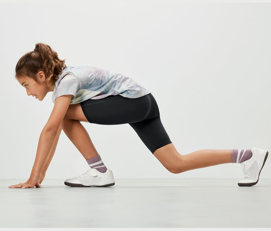 Mädchen in Sportposition trägt 2 Kinder-Sport-Radler in Schwarz.