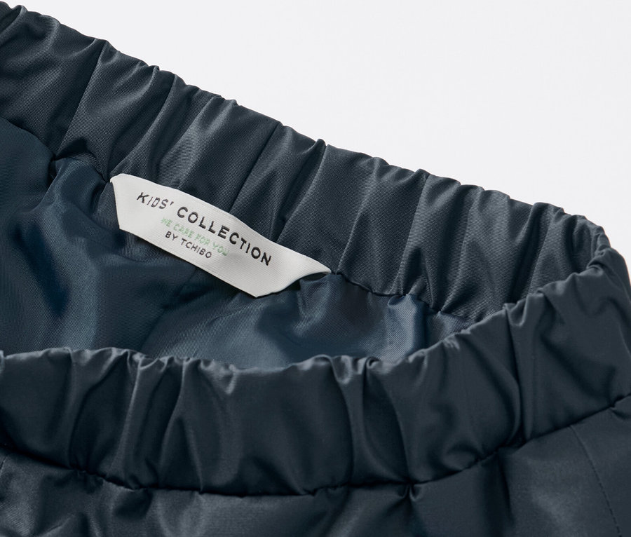 Detailaufnahme einer dunkelblauen Kinder-Regenhose mit Gummibund und Kids' Collection Etikett.